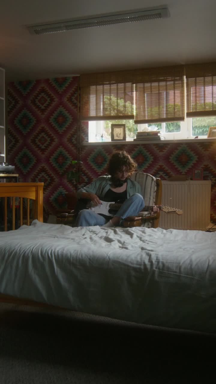 una adolescente tocando la guitarra eléctrica en el dormitorio