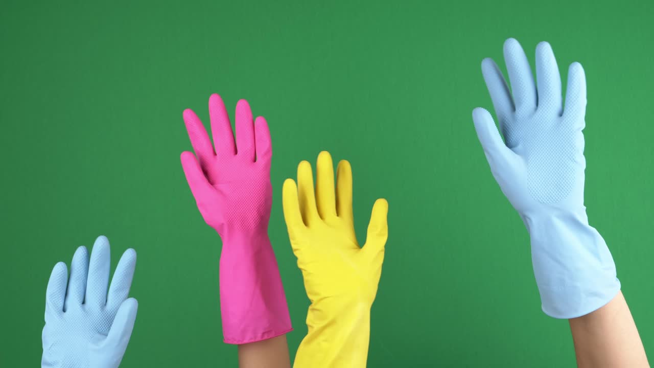보호용 고무 장갑을 입은 손이 일어나서 손을 흔들며 인사를 하고, 크로마 키 녹색 스크린 배경에 손짓을 합니다.