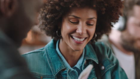 Schöne-Frau-Mit-Afro-Look,-Die-Mit-Einem-Freund-Im-Café-Chattet-Und-Smartphone-Social-Media-Nachrichten-Zeigt.-Beste-Freunde-Hängen-Herum,-Teilen-Klatsch-Und-Genießen-Die-Verbindung