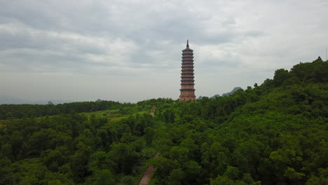 experience a sweeping panoramic view of the forest path leading to the majestic bái đính pagoda in ninh binh, vietnam, under a soft, overcast sky. discover the natural beauty surrounding.