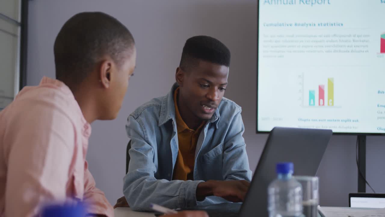 To seriøse afroamerikanske kolleger diskuterer under et møde ved brug af laptop og skærm.