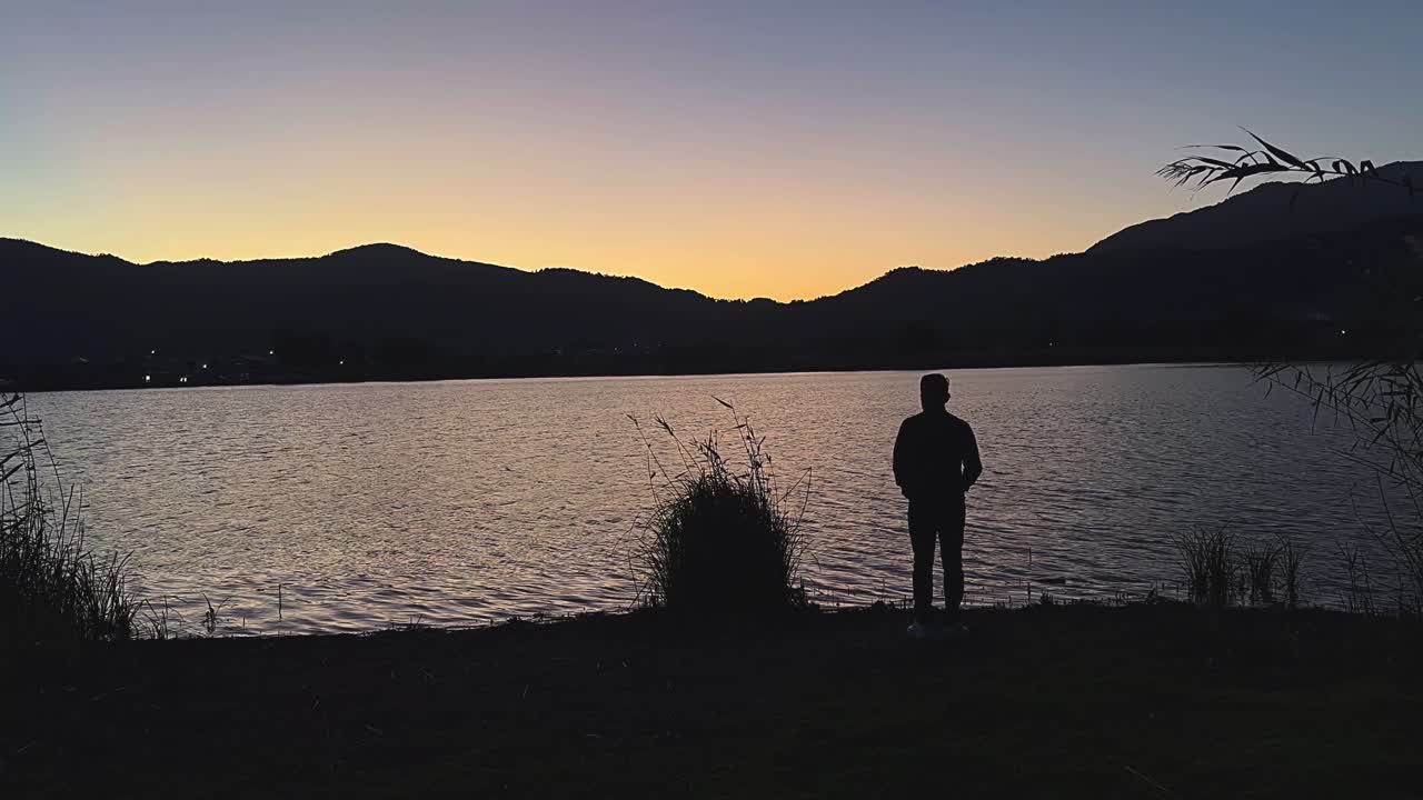hombre contemplando la puesta de sol sobre el lago