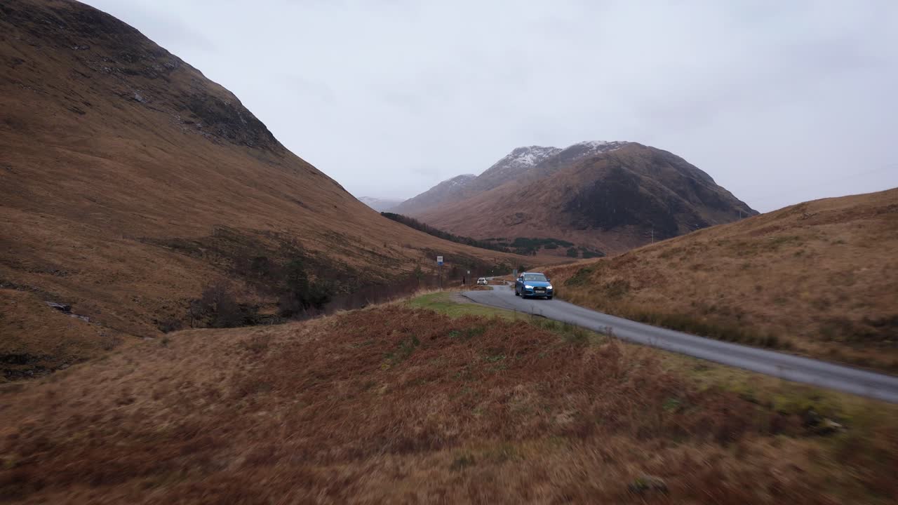 Car drive through red grass moorland in spectacular scenery of Scottish Highlands