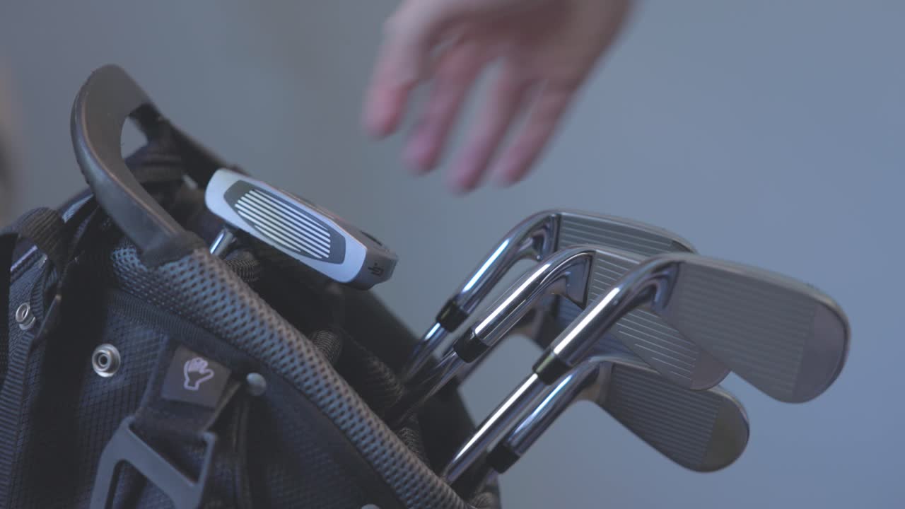 close-up shot of a golfer putting a putter back in his golf bag