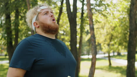 Obese-Man-Taking-Break-and-Drinking-Water-on-Run-in-Park