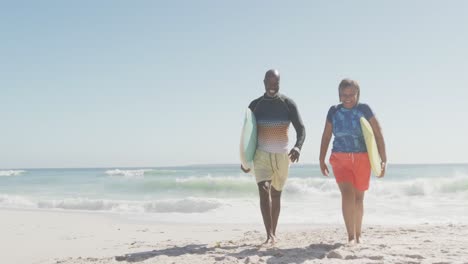 Feliz-Pareja-Afroamericana-Senior-Caminando-Con-Tablas-De-Surf-En-La-Playa-Soleada