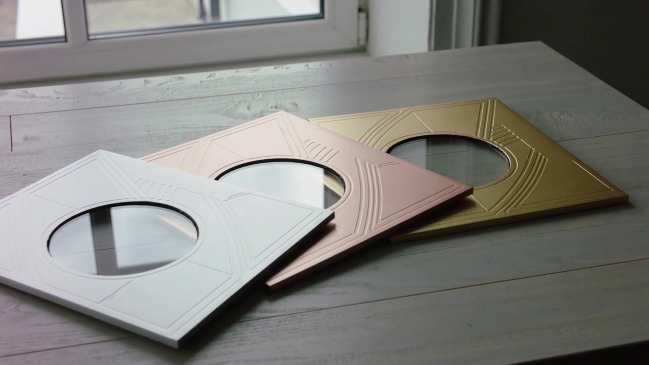 Eine gleitende Kamera enthüllt drei geprägte Metallplatten auf einem Holztisch, um die goldene Platte hervorzuheben.