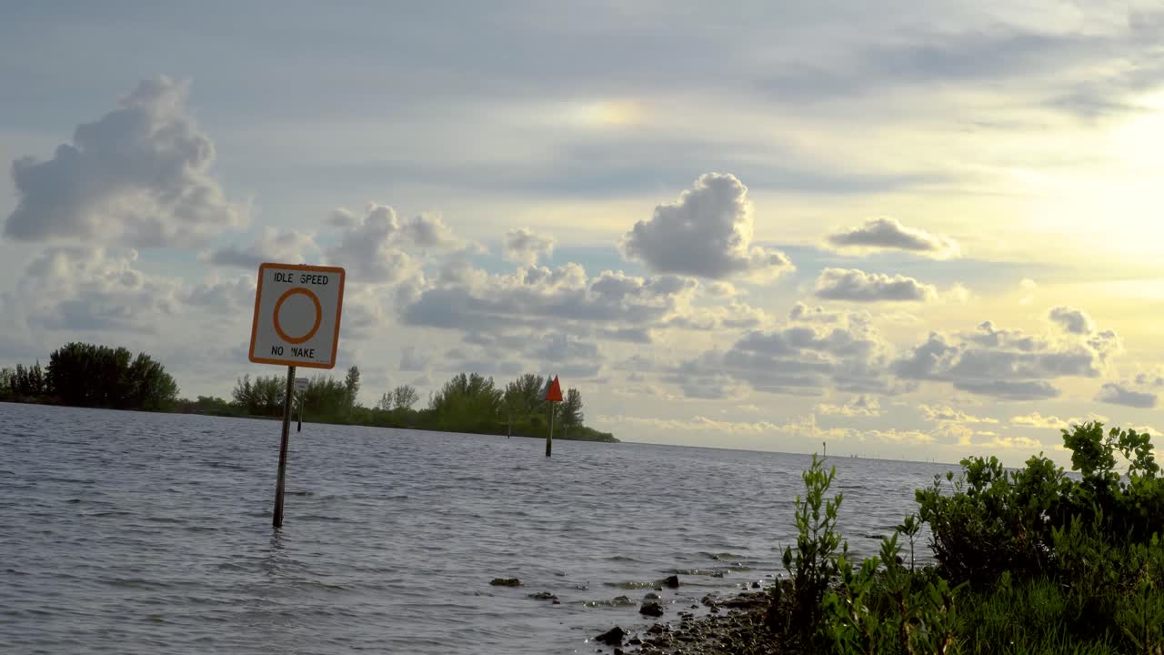 Gulf Coast waterway with idle speed and no wake sign on wood pole marker