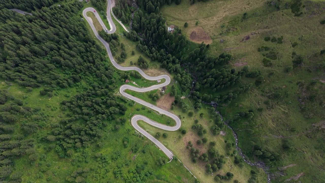 Aerial view showcasing the dramatic curves of Passo Giau mountain pass, framed by the striking Ra Gusela summit in the Italian Alps