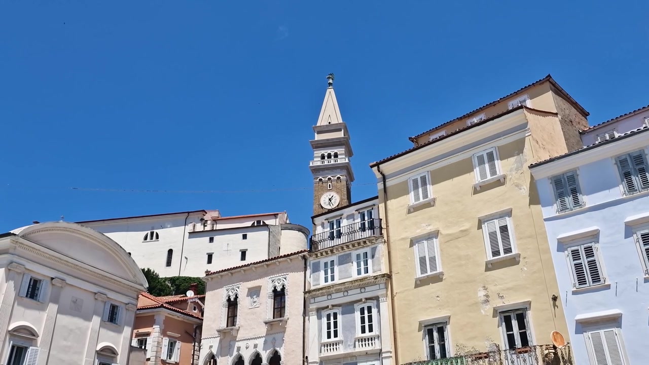 Pirano, Slovenia. Edifici del centro intorno a Piazza Tartini e Torre dell'Orologio e Campanile Veneziani in una calda giornata di sole.