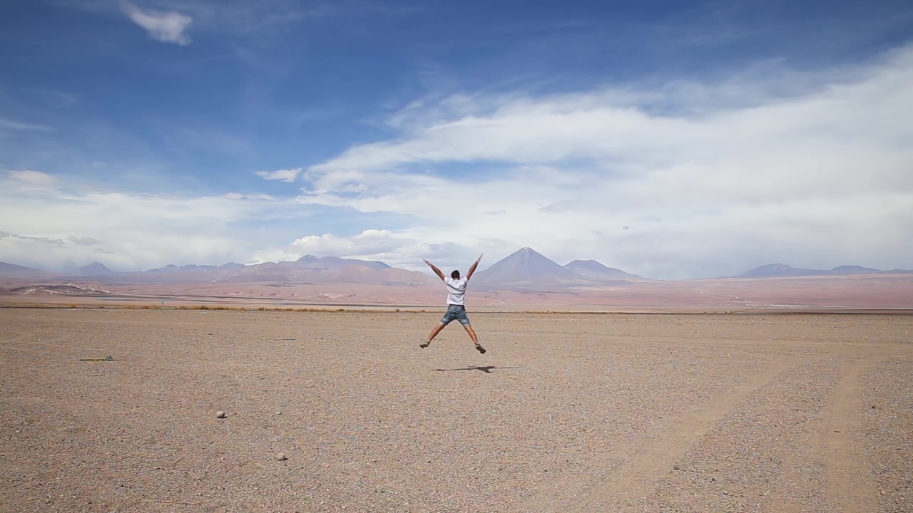 Un uomo salta in un paesaggio desertico in una giornata di sole