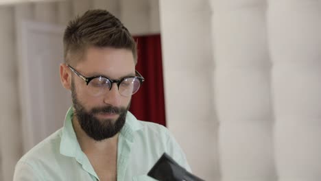 man with beard styling his hair with a hair dryer