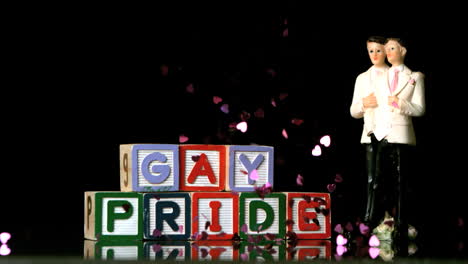 confetti falling on blocks spelling gay pride with gay cake topper