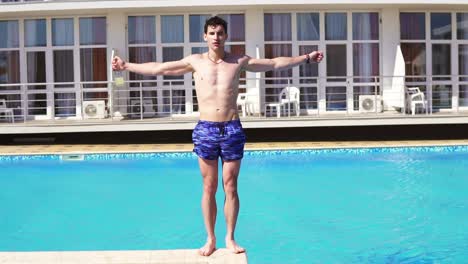 Junger-Athletischer-Mann-In-Badeshorts,-Der-In-Den-Schwimmbad-Fällt