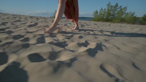 camera turning around a woman walking barefoot in the sand on a beatiful sunny light in sandbanks