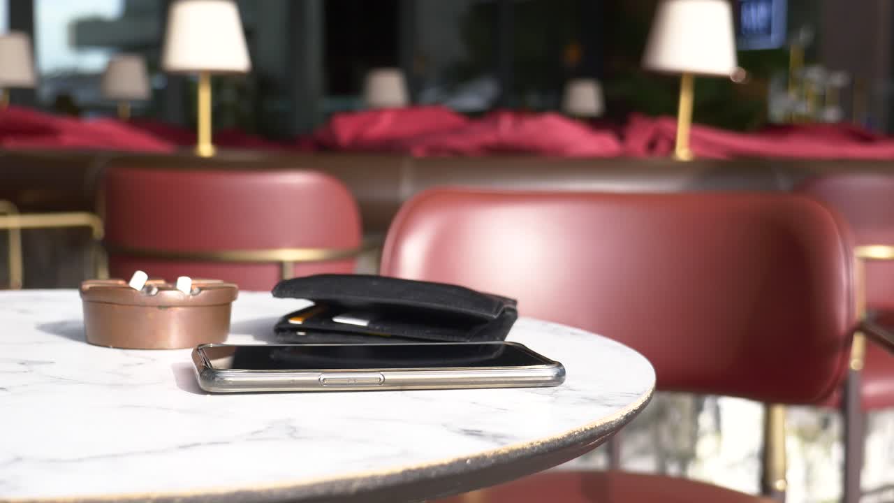 Smartphone, wallet, and credit cards on a marble table in a cafe
