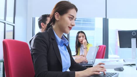 empleado asiático oficial atractiva sonrisa positiva mujer trabajando en el escritorio con fondo de oficina moderna