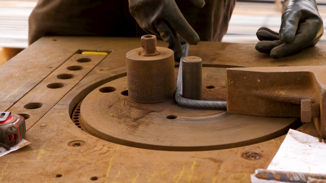 Piegatura di tondini d'acciaio con macchina industriale per la fabbricazione manuale, primo piano.