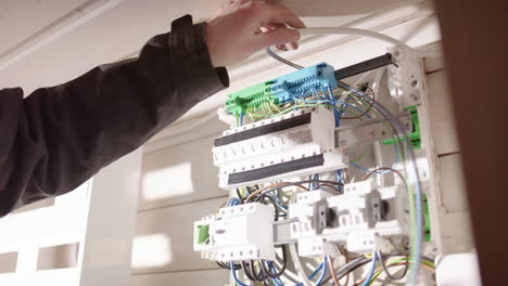 electrician placing loose wires in electric panelboard before connecting them