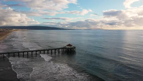 drone shot orbiting the manhattan beach pier and city in california, america