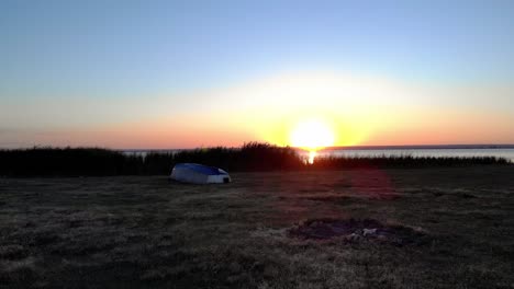 Holzboot-In-Der-Nähe-Eines-Ruhigen-Sees-Mit-Sonnenaufgangsreflexion