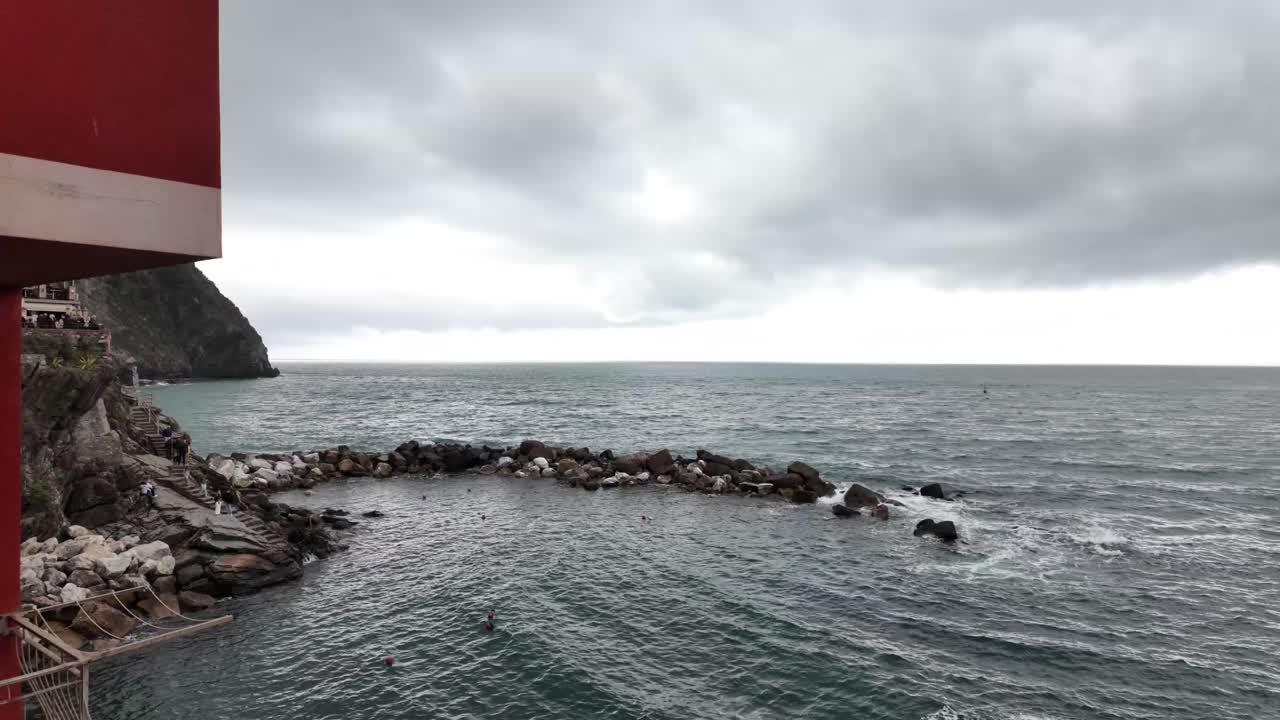 이탈리아의 리오마지오레 마을에서, 벽 너머의 바다는 평온한 해안의 아름다움을 포착합니다.