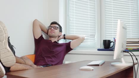 young businessman finishing his work on his computer and stretching his arms in office. short break in the office. 4k shot