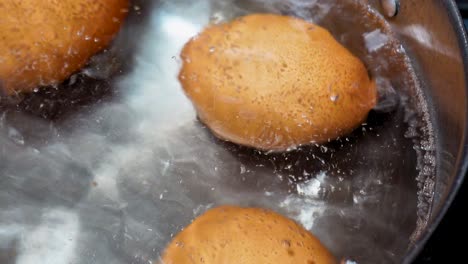 close-up: eggs boiling in pot on gas burner