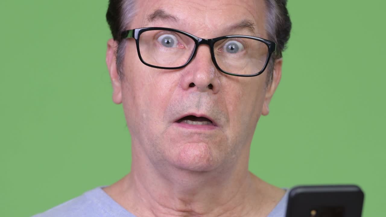 Senior handsome man using phone and looking surprised