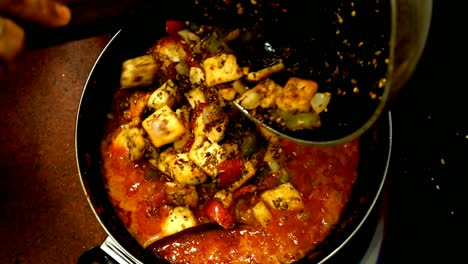 mujer de cerca añadiendo masala asado queso cottage paneer en la salsa