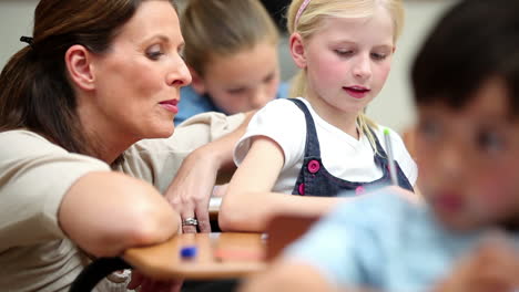 happy teacher helping a blonde pupil