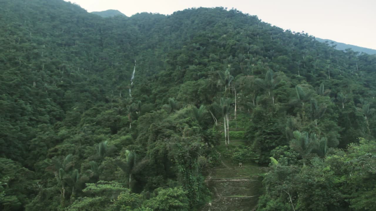 Wide tilt up shot of a beautiful and untouched waterfall in the ancient Tairona site of Ciudad Perdida, deep in the Sierra Nevada de Santa Marta, Colombia