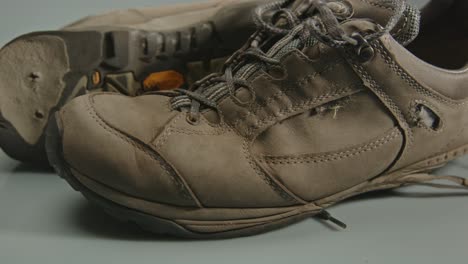 wide dolly of worn hiking shoes with holes and torn soles against a studio background