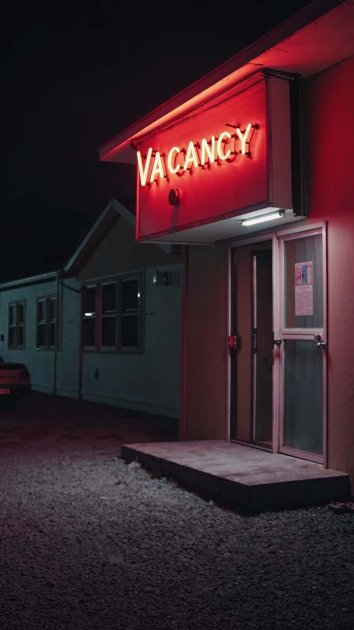 Moody nighttime video scene of a motel with a glowing 'Vacancy' sign