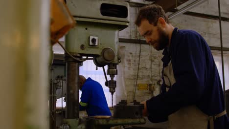 metalsmith using drill press machine in workshop 4k