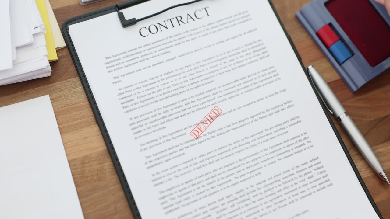 Hand Stamping 'Denied' on a Business Contract Document