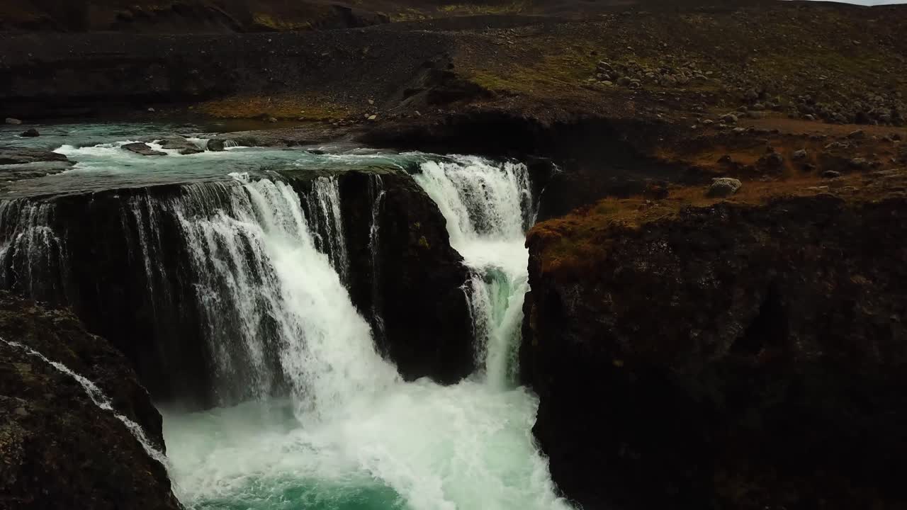 vista aérea de un dron sobre el agua que fluye por una gran cascada, en islandia