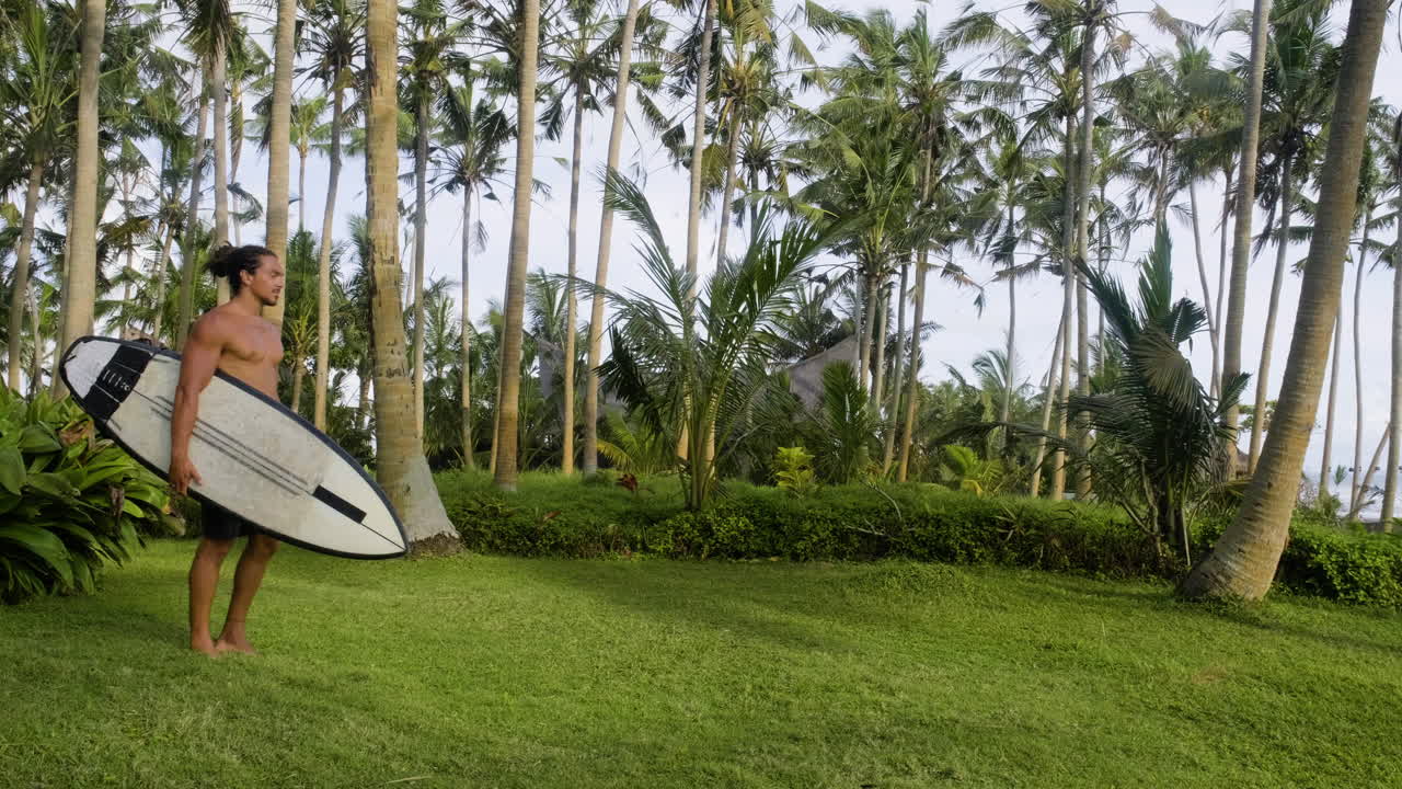 человек, идущий и держащий доску для серфинга.