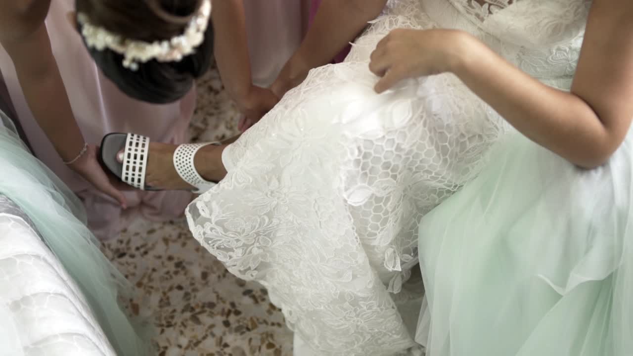 Bridesmaid putting the shoe on the toe of the bride on the wedding day