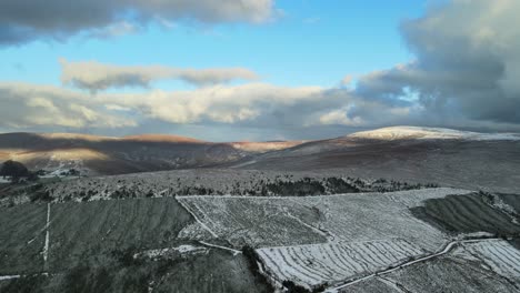 snowy mountain landscape with sunlit peaks and clouds, aerial view