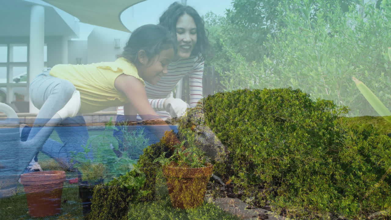 Gardening together, mother and daughter planting flowers in lush green landscape