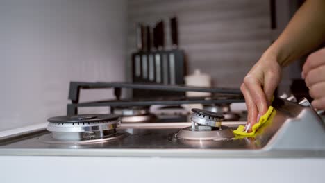 woman's hand cleaning metal cooker. cleaning gas stove in the kitchen. pure surface of a gas cooker. householding concept. close-up.