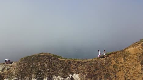 couple hiking on coastal cliff in fog