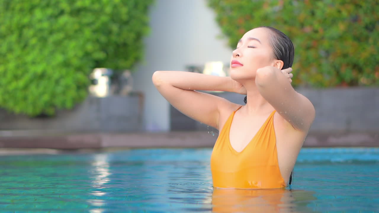 섹시한 젊은 여성이 수영하다가 젖은 머리를 뒤로 젖힌다
