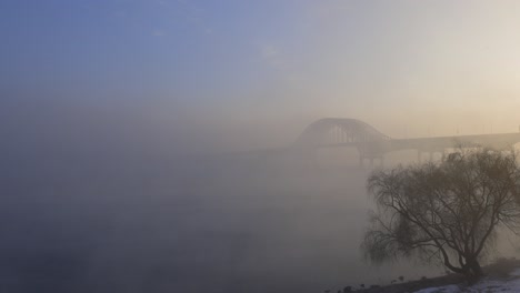 misty bridge over river at sunrise