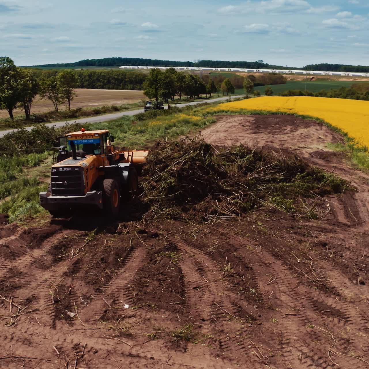 Tractor working on the field. Agricultural machine among nature. Yellow field in the countryside in summertime.