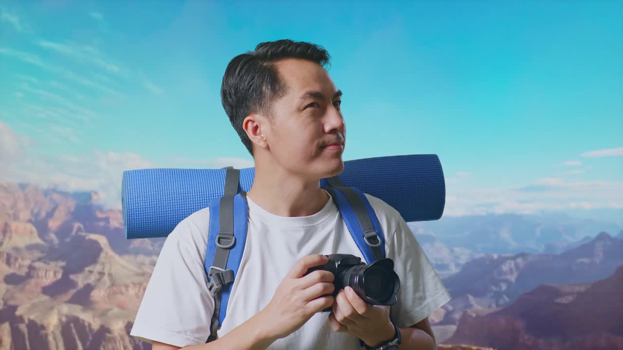 Close Up Of Asian Male Hiker With Mountaineering Backpack Holding A Camera In His Hands Then Looking Around While Traveling At The Top Of Mountain