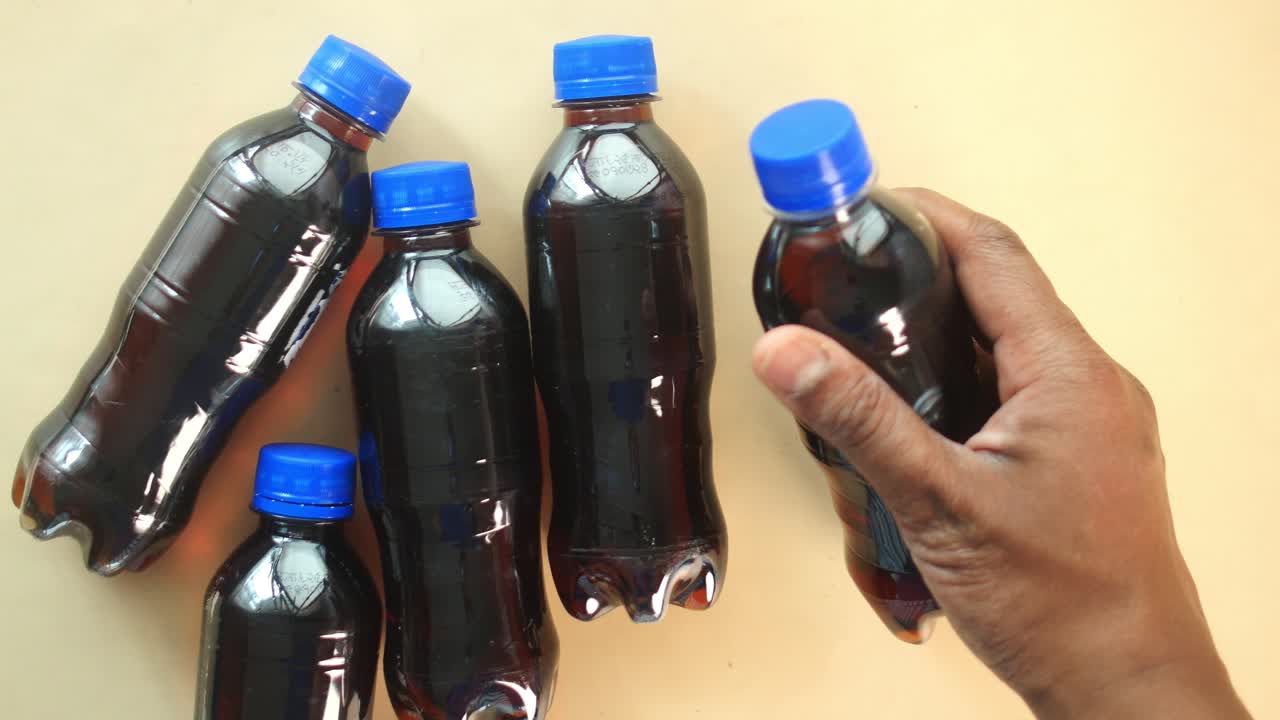 Hand holding a bottle surrounded by other similar soda bottles