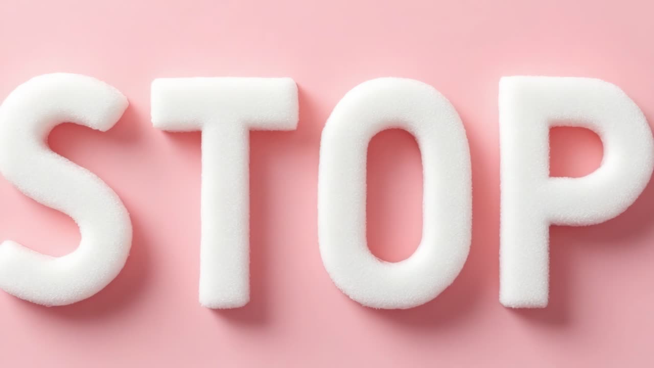 White foam letters arranged to spell STOP are placed on a soft pink background, creating a striking visual contrast that emphasizes the importance of stopping and taking notice