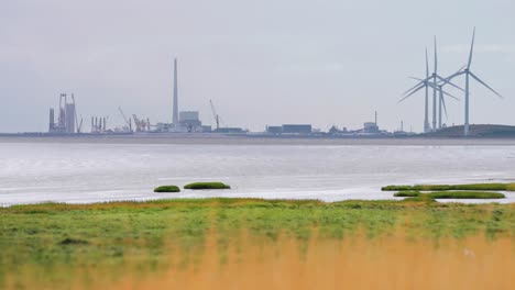 Eine-In-Dunst-Gehüllte-Stadt-Und-Rotierende-Windkraftanlagen-An-Der-Dänischen-Küste